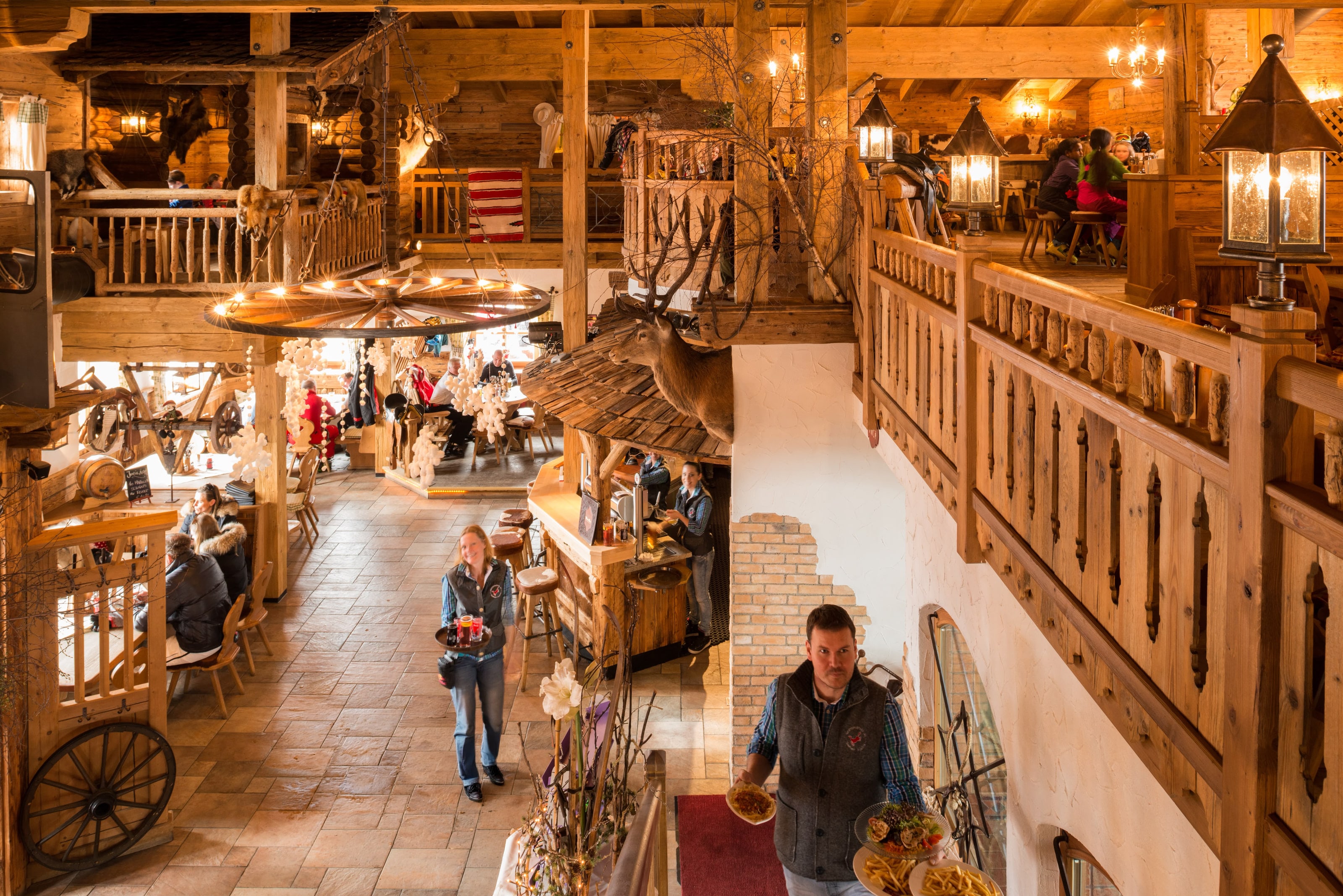 Blick über die zweistöckige Holzstube des Westernstadl mit Galerie, Laternen und gedeckten Tischen
